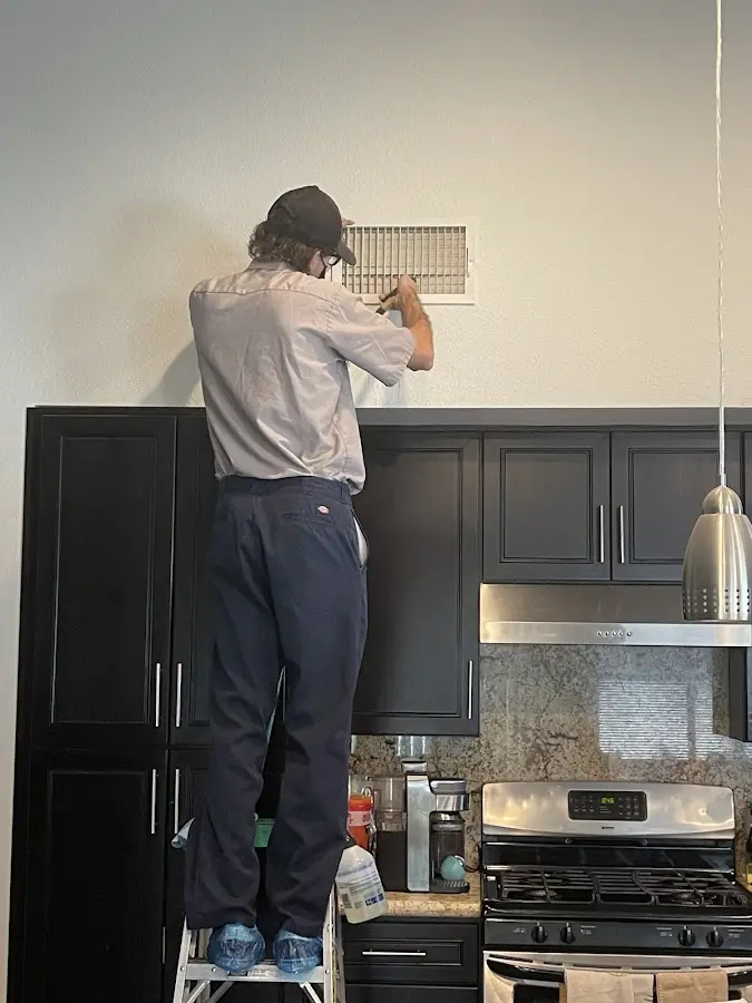 Technician inspecting an air vent during HVAC service in Providence